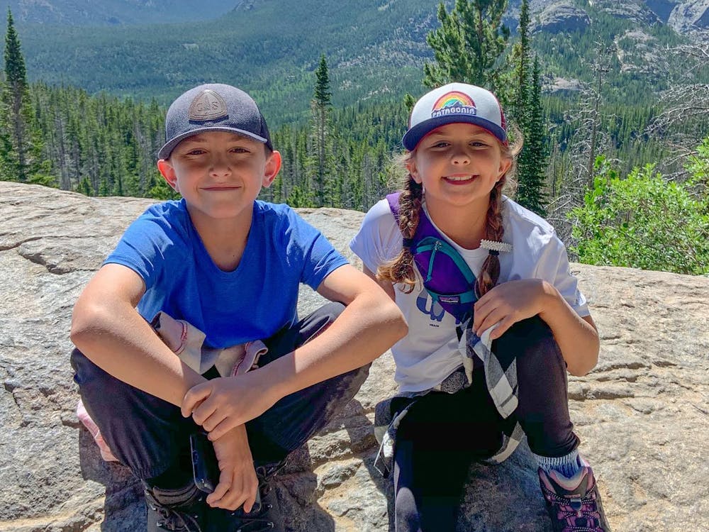 kids sitting on a large rock smiling at camera