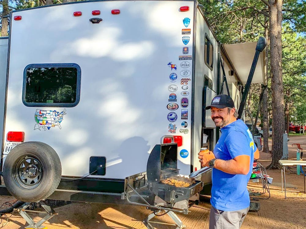 Man cooking outside of Keystone Bullet travel trailer