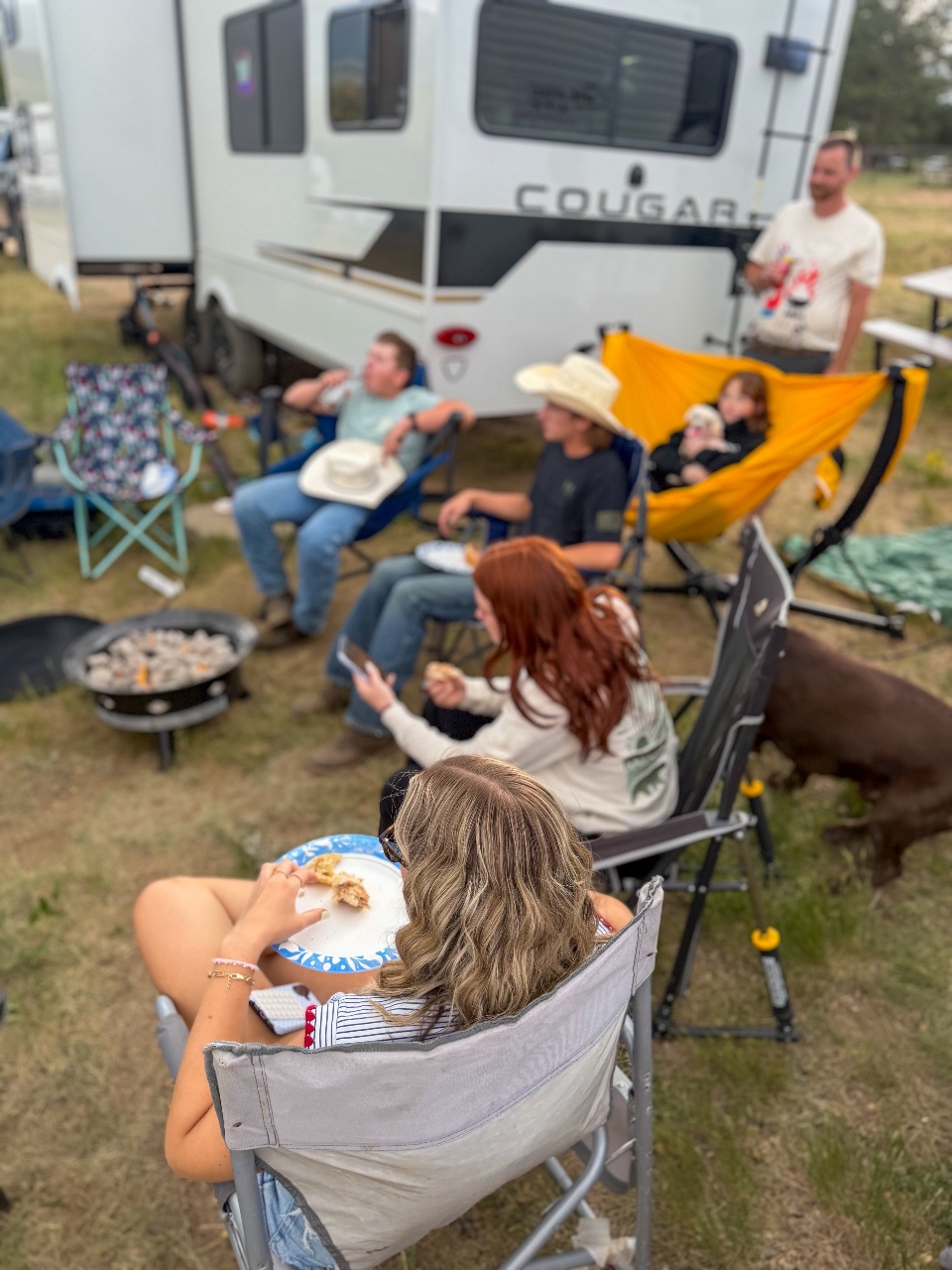 Family eating dinner around fire.