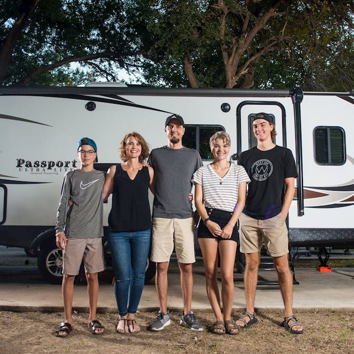 Family standing in front of thier Keystone Passport RV travel trailer.