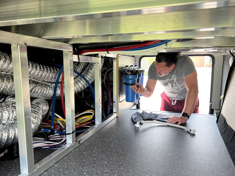 Owner checking water filter system on Arcadia RV