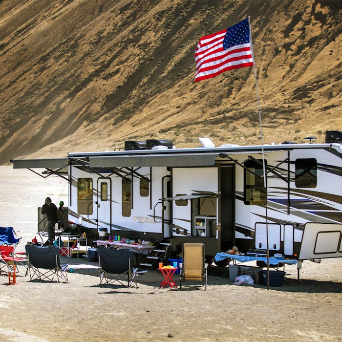 Keystone Fuzion toy hauler RV in desert with dirt bikers.